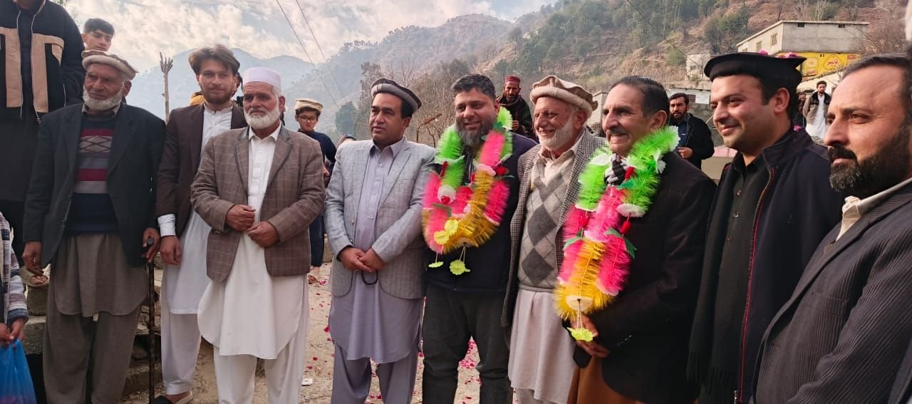 Dr. Ahmed Ejaz wearing a garland among community elders in the hills