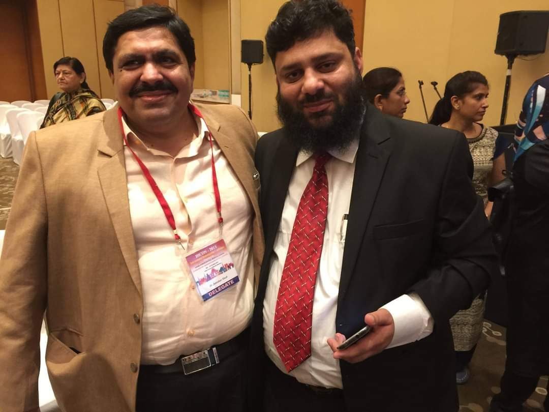 Dr. Ahmed Ejaz with a colleague at a conference, both wearing delegate lanyards