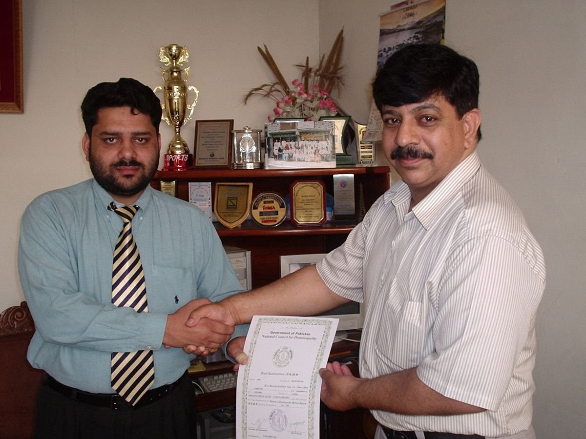 A young Ahmed Ejaz shaking hands while receiving his DHMS final examination certificate