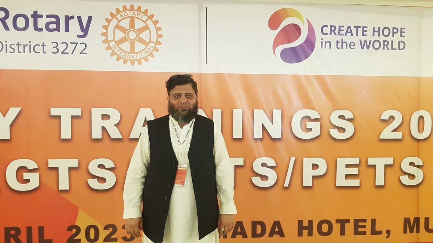 Dr. Ahmed Ejaz in front of a District 3272 training banner in Murree