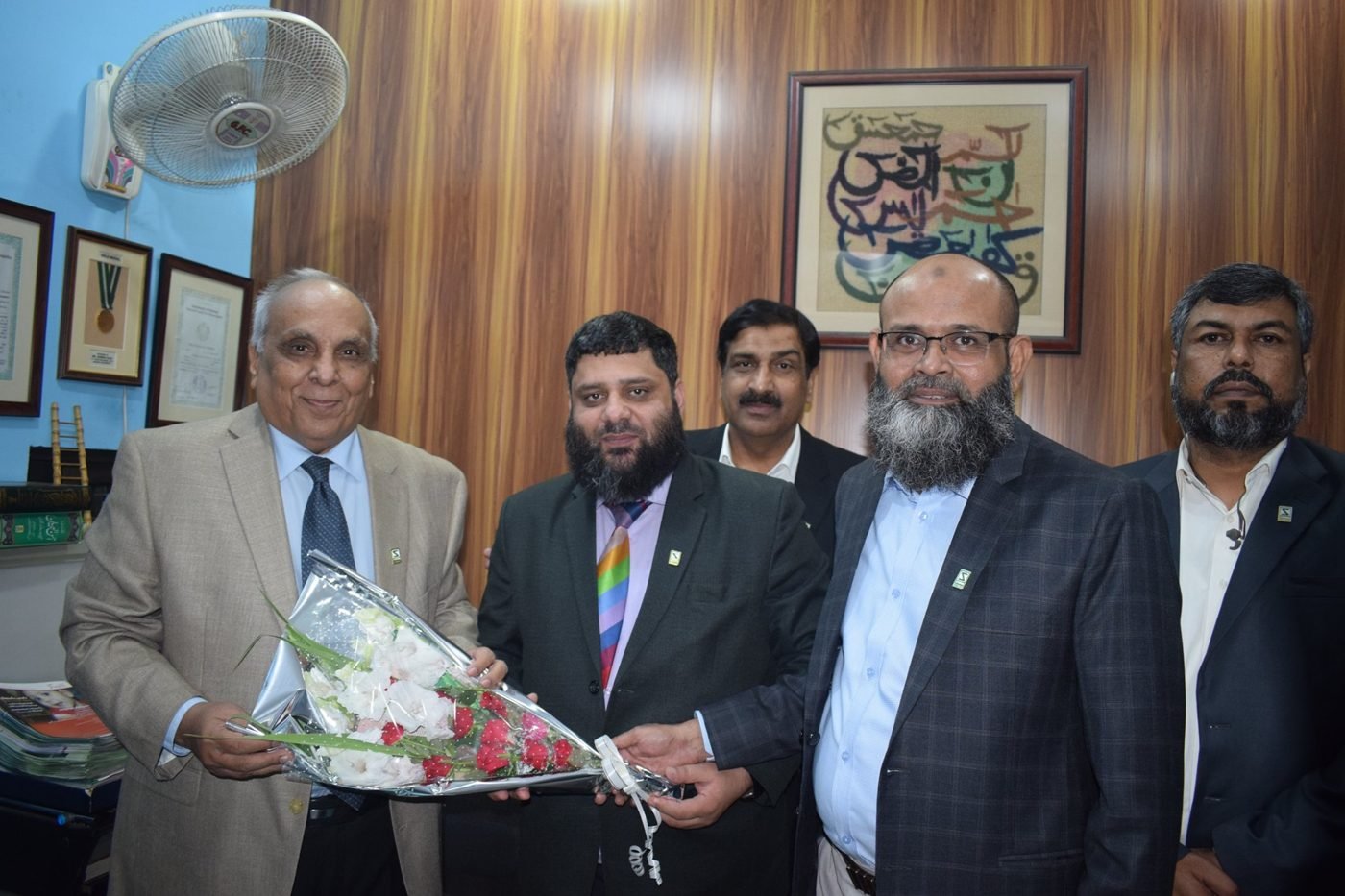 Dr. Ahmed Ejaz receiving a bouquet from a senior guest among colleagues